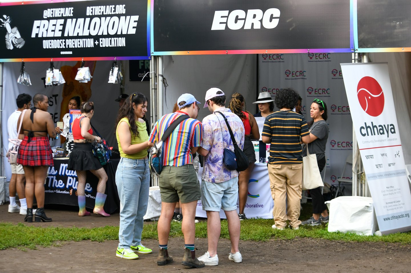 People interact at community organization booths during an outdoor public event.