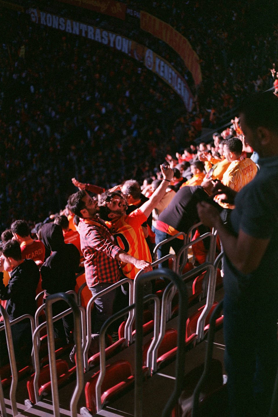 Sports fans cheer during a match in a crowded stadium.