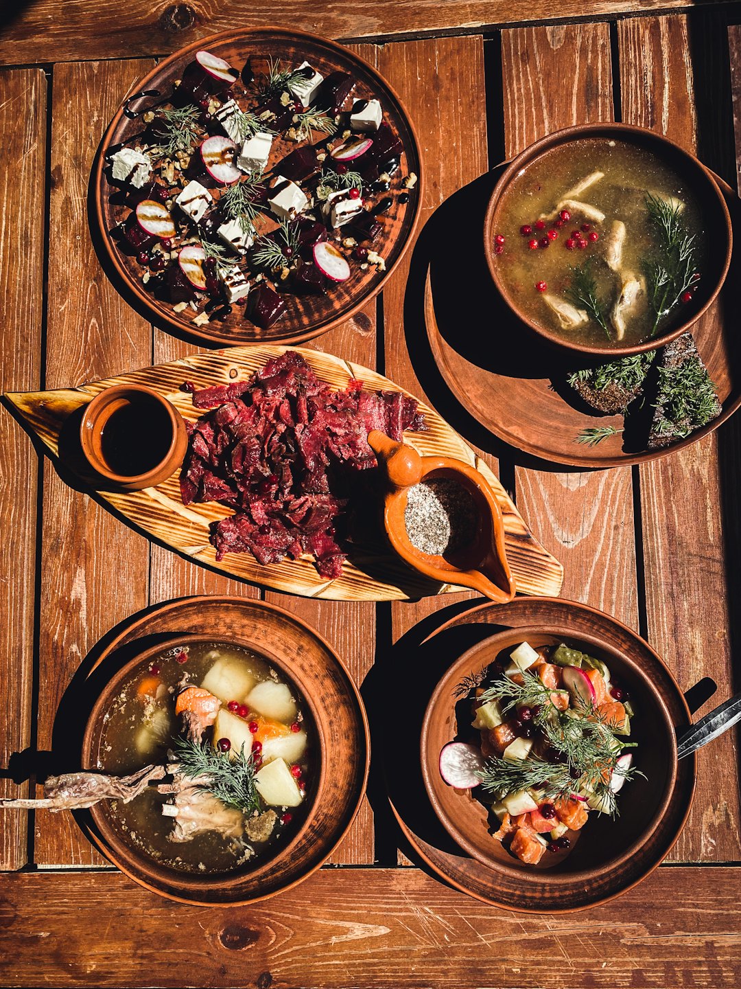 Rustic dishes with soup and salads arranged on a wooden table.