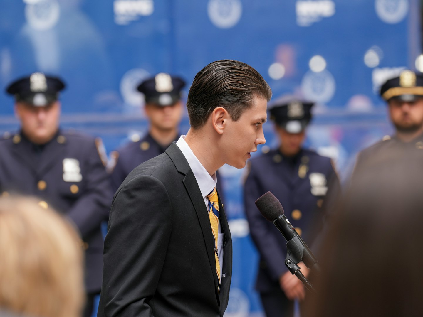 Man in suit speaks into microphone at press conference.